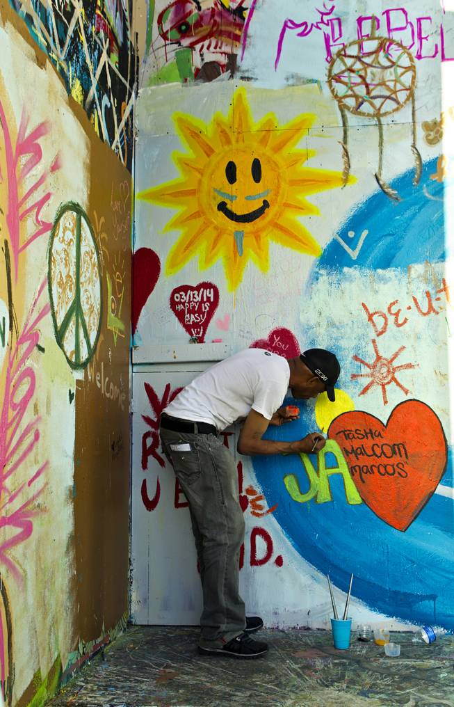 Artist Johnnie Reaves paints his own creation to the Life Cube project including the names of his children on Friday, March 14, 2014.